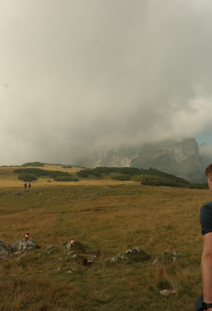 Wanderer auf der Hochalm vor nebelverhangenen Felswänden im Rofan auf dem Weg zum Zireinser See
