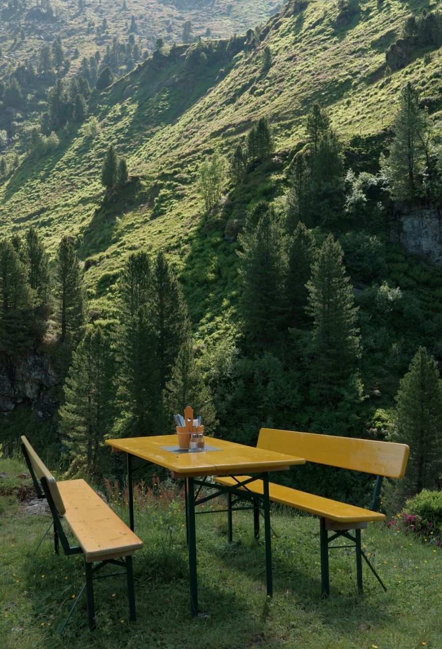 Gelbe Sitzgruppe vor einem bewaldeten Berghang bei der Neuen Bamberger Hütte