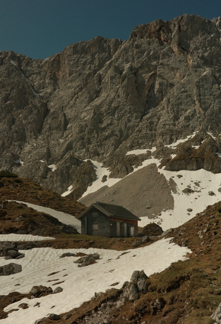 Kleine Berghütte zwischen Schneefeldern unter den Felswänden am Lamsenjoch